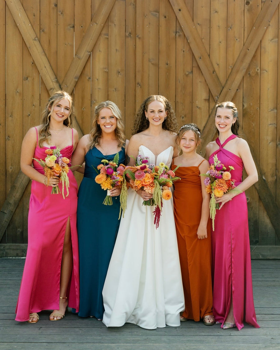 Bride and Bridesmaids at Trezzi Farm Winery dressed in rich autumn hues and holding their custom bouquets by their Spokane Wedding florist.