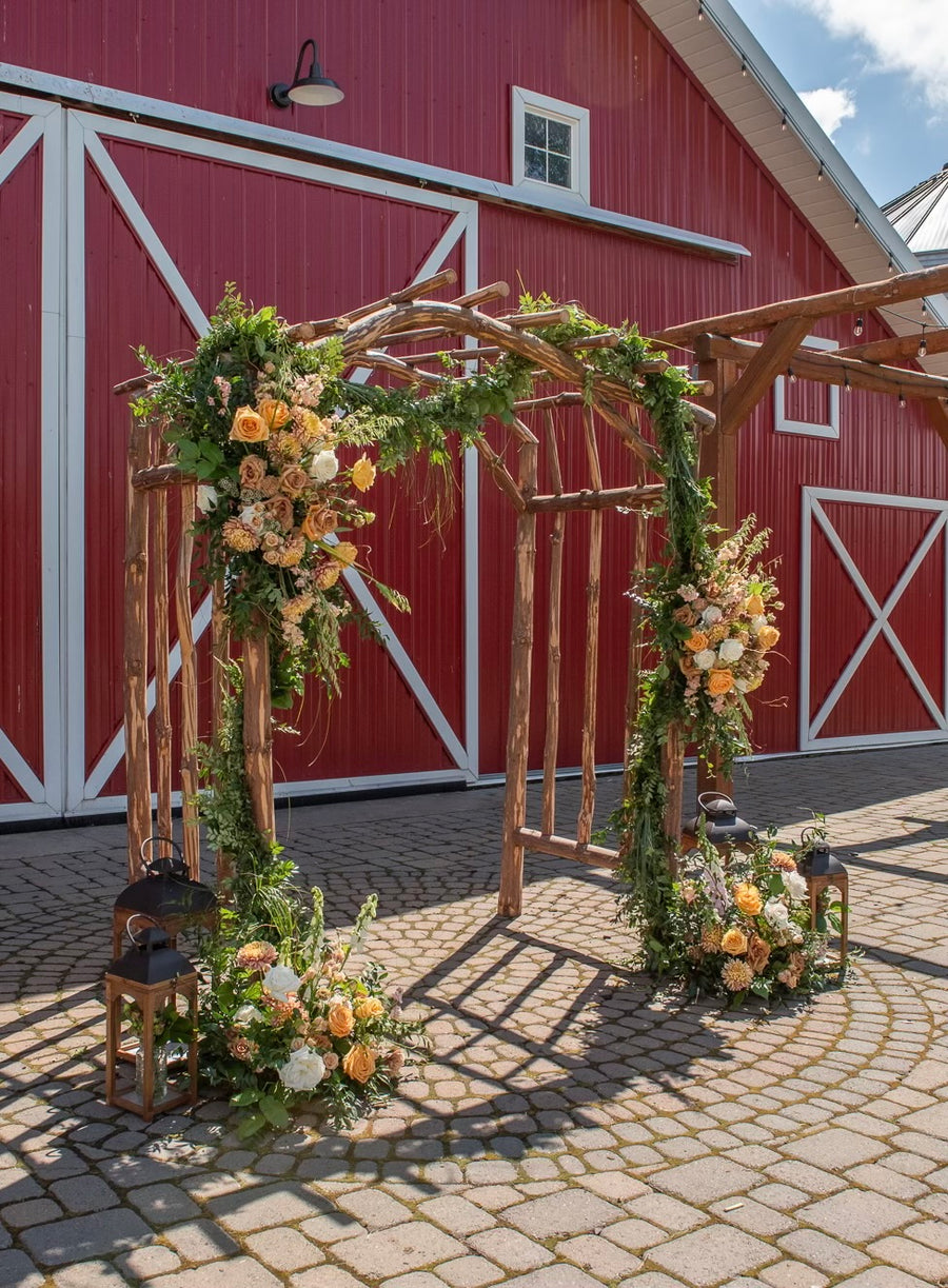Stunning rustic wedding arch adorned with yellow, gold and cream flowers by Daisies in May