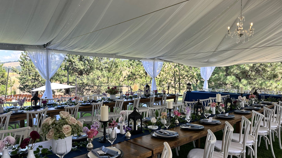 Dining setup under a large white tent with tables, chairs, and decorated with seasonal florals for a Eastern, WA wedding