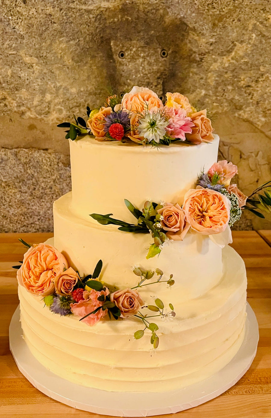 Wedding cake with wildflowers decorating it by Daisies in May wedding florist